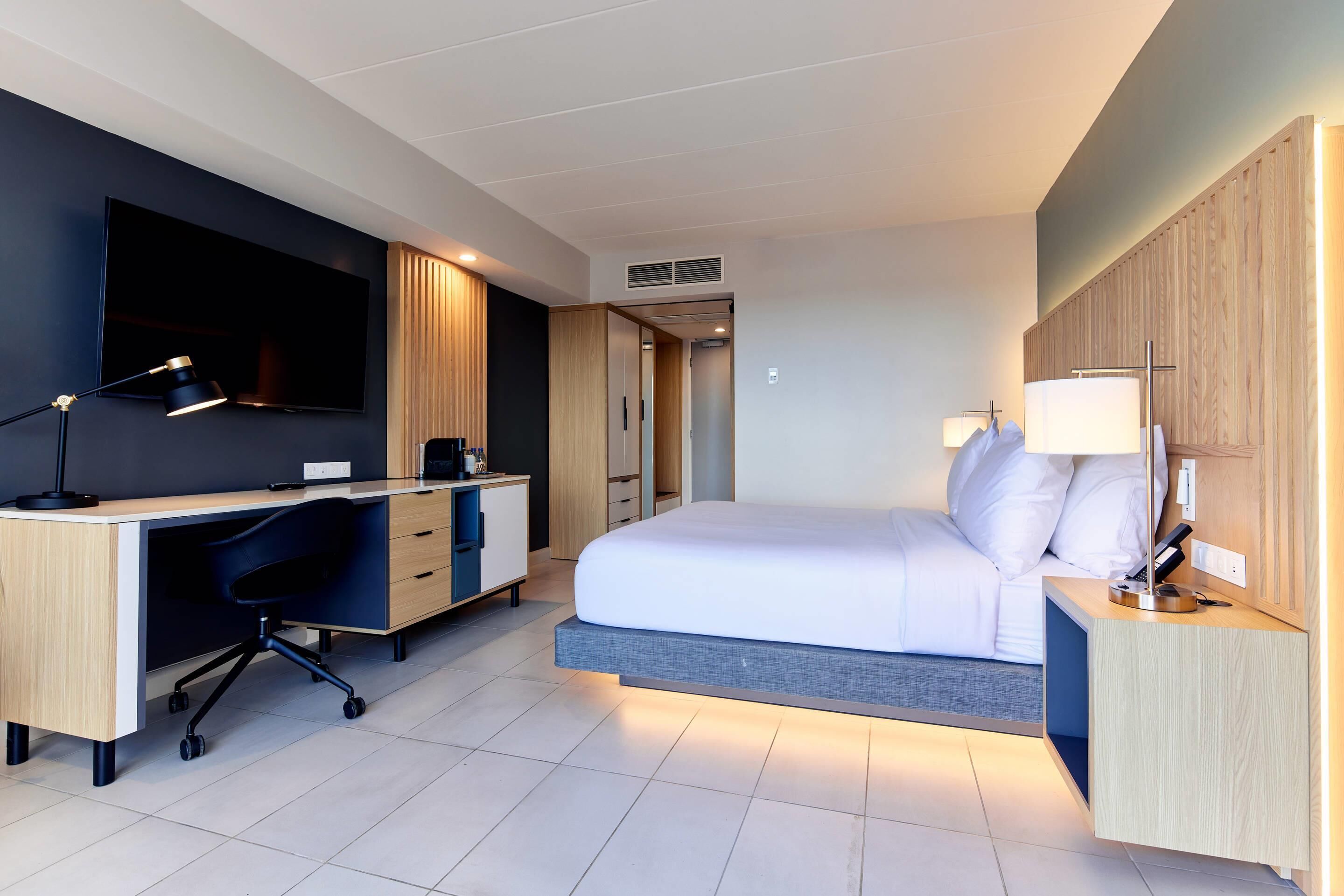 Una habitación de hotel moderna con cama, escritorio y televisión.