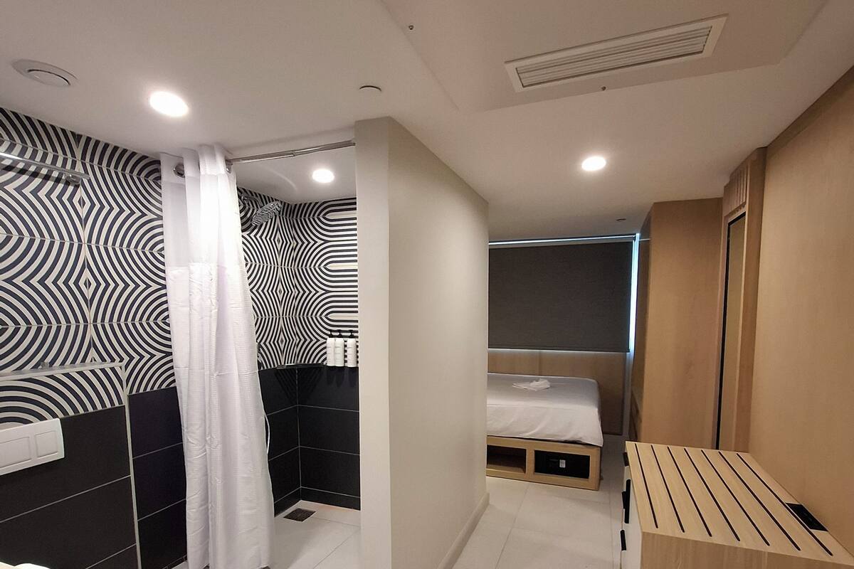 A modern bathroom with a shower, toilet, and a small bed in the corner.