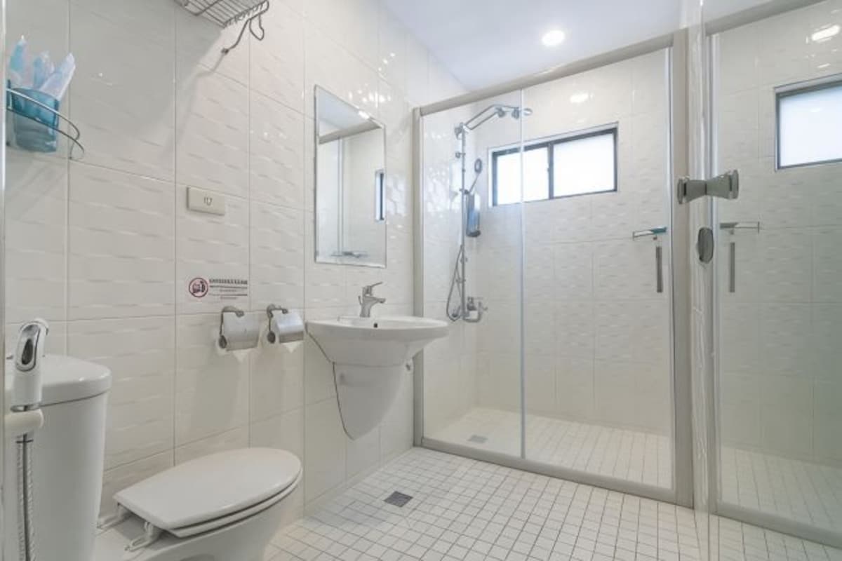 A modern bathroom with a toilet, sink, and glass-enclosed shower.