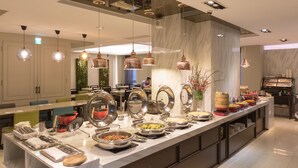 A buffet setup with various food items and utensils. - Just Enjoy Business Hotel (Tainan)