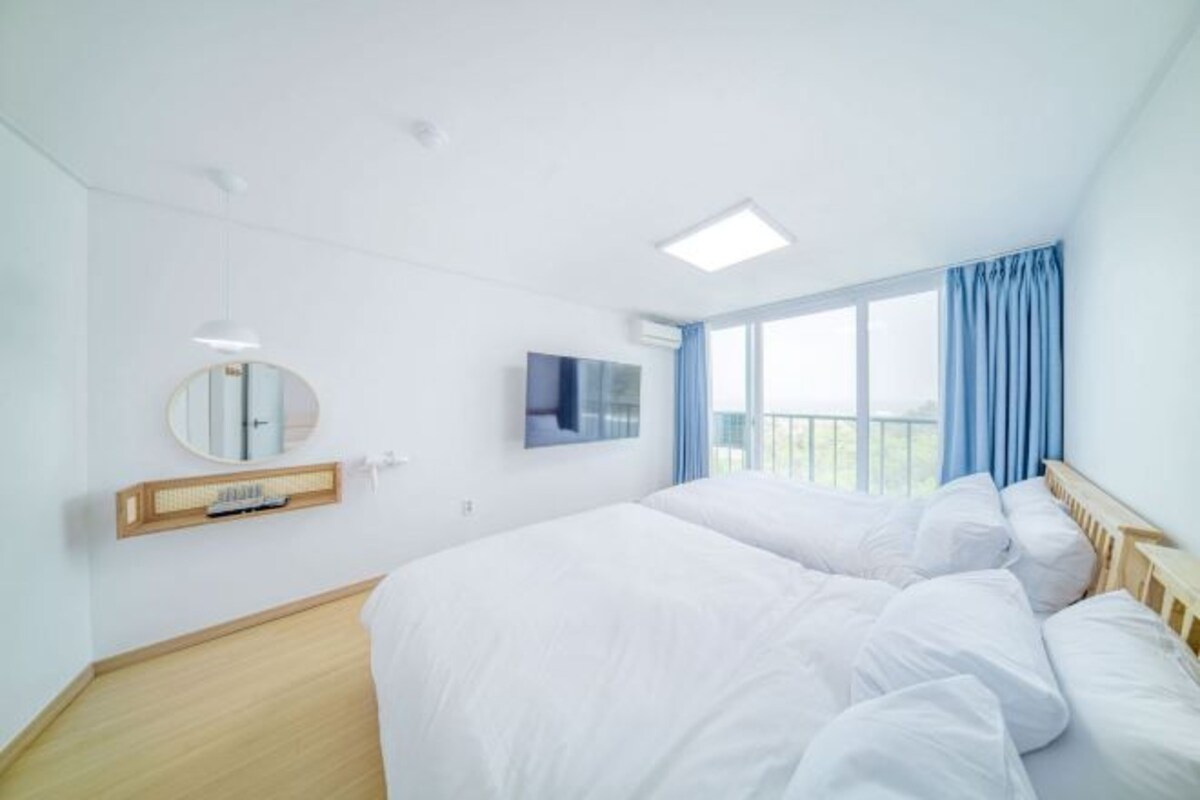 Une chambre d’hôtel avec un grand lit, une télévision, un miroir et une fenêtre avec des rideaux.
