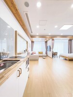 A modern hotel room with a kitchenette, a sofa, a bed, and a dining area.