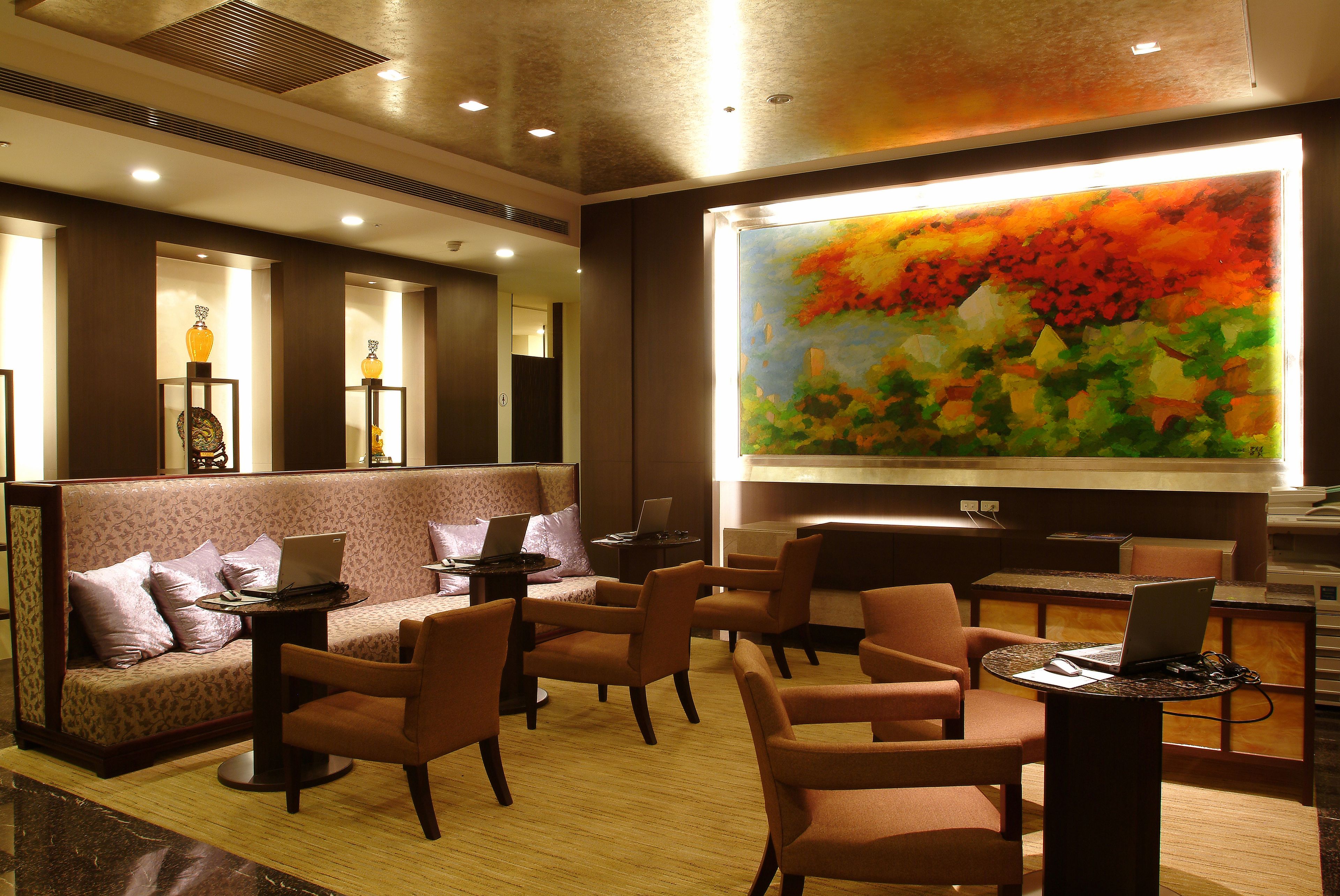 Eine Lobby mit einer Couch, Sesseln, einem großen Gemälde und einer Rezeption.