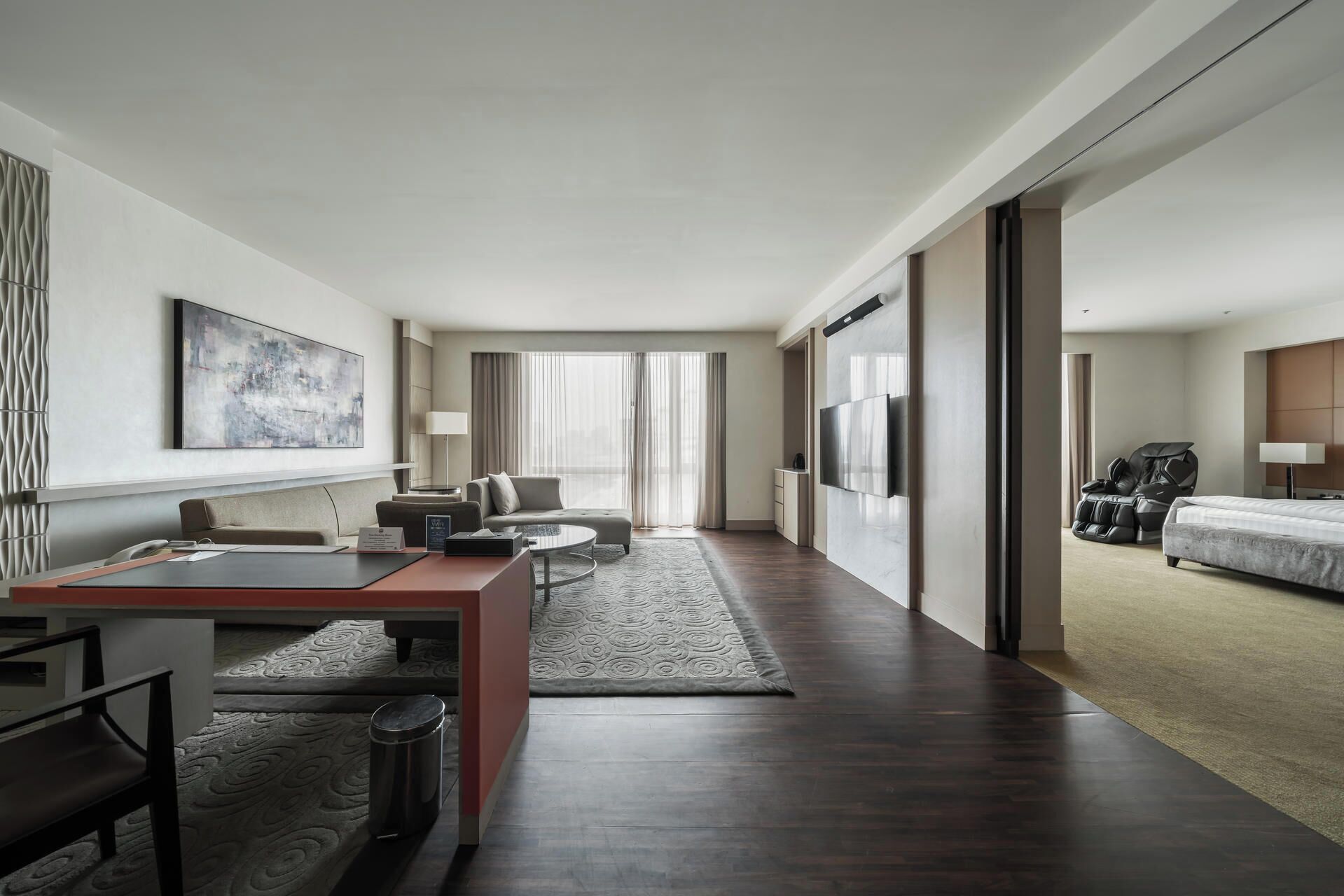 A modern hotel room with a desk, sofa, and massage chair.