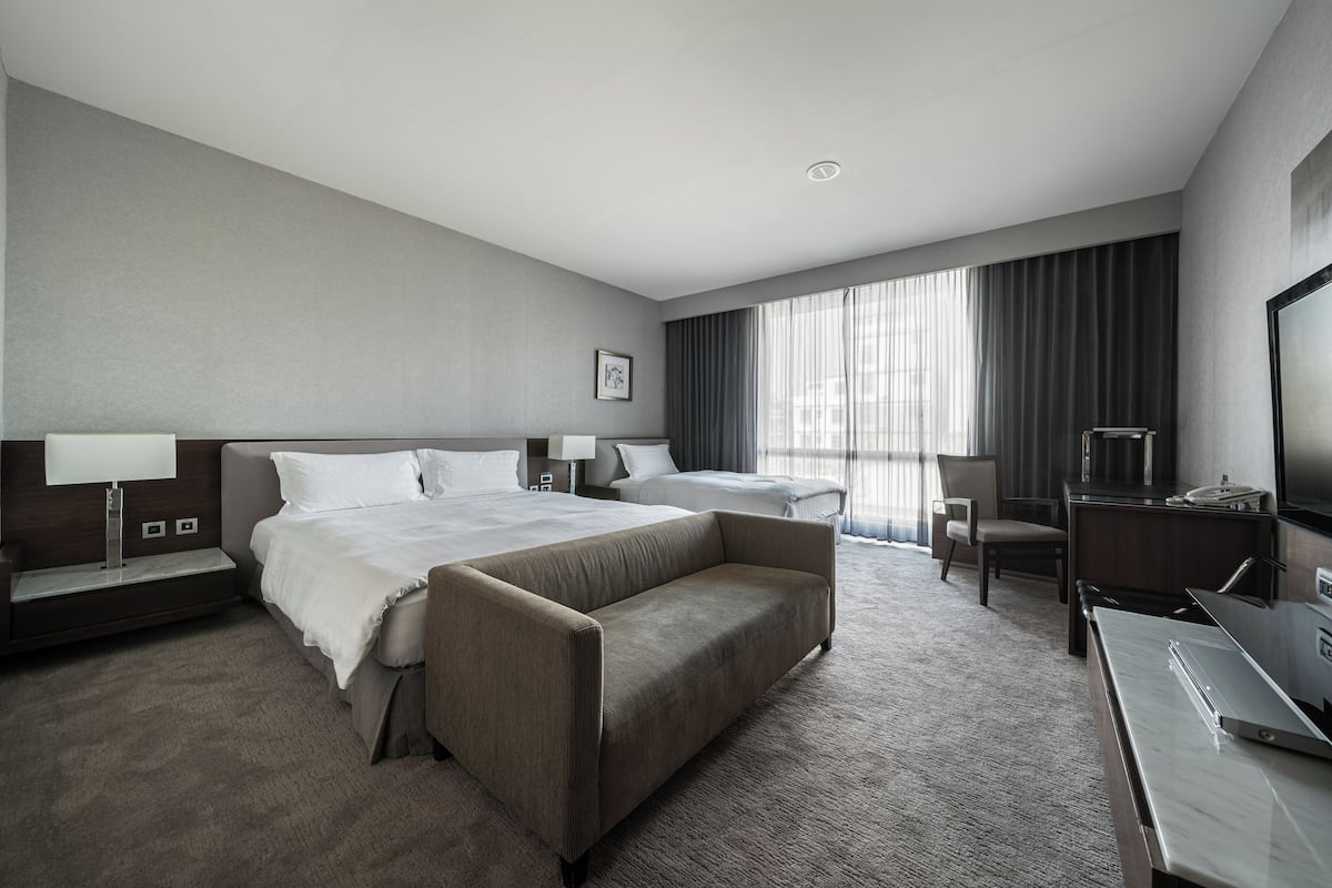 A hotel room with a large bed, a sofa, a desk, and a TV.