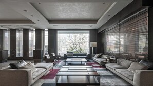 Uma sala de estar moderna com sofás, uma mesa de centro e uma janela grande com persianas.