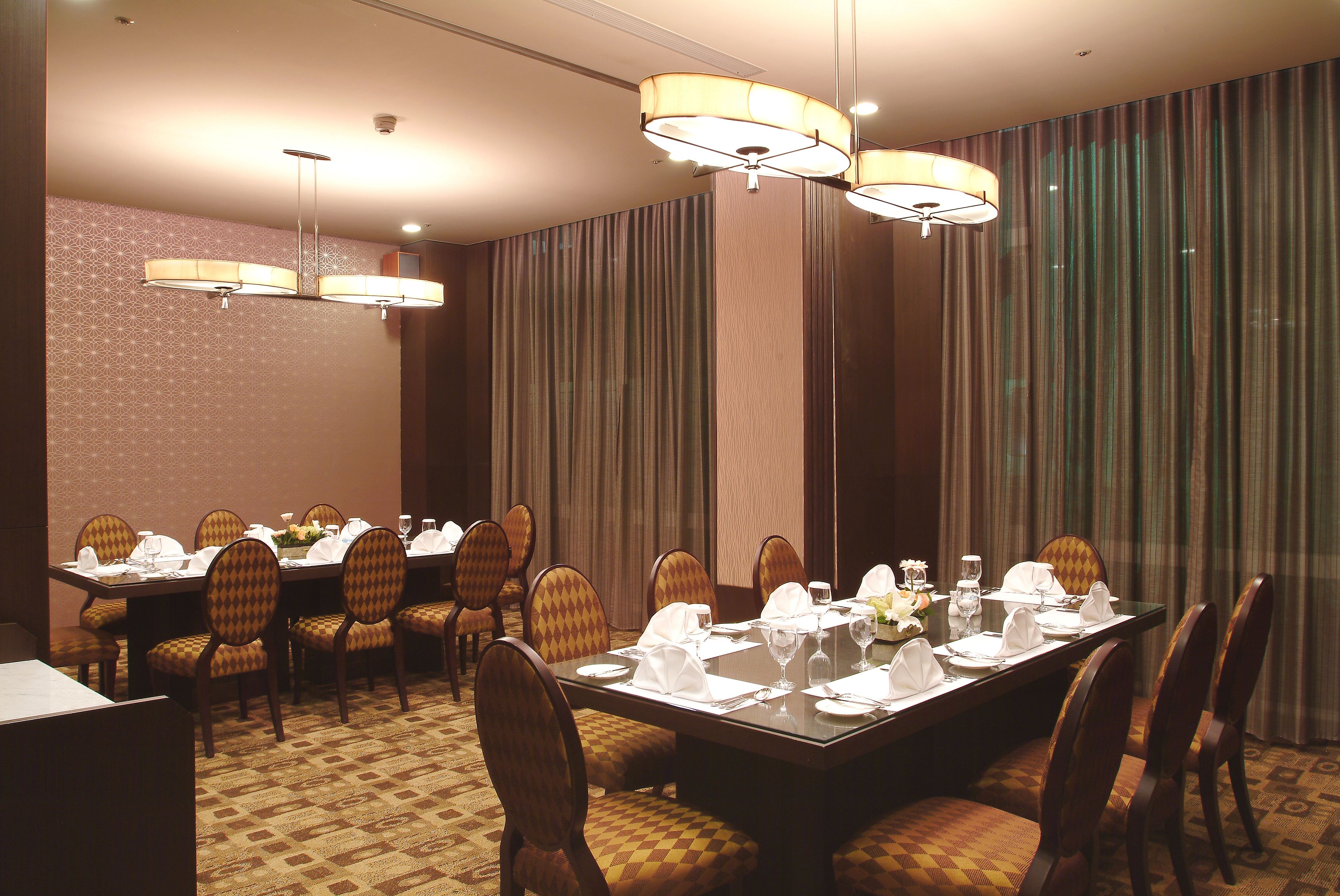 A conference room with a large table set for a meeting, surrounded by chairs, and equipped with chandeliers.