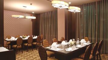 A conference room with a large table set for a meeting, surrounded by chairs, and equipped with chandeliers.