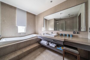 A modern bathroom with a large bathtub, a walk-in shower, and a vanity with a large mirror.
