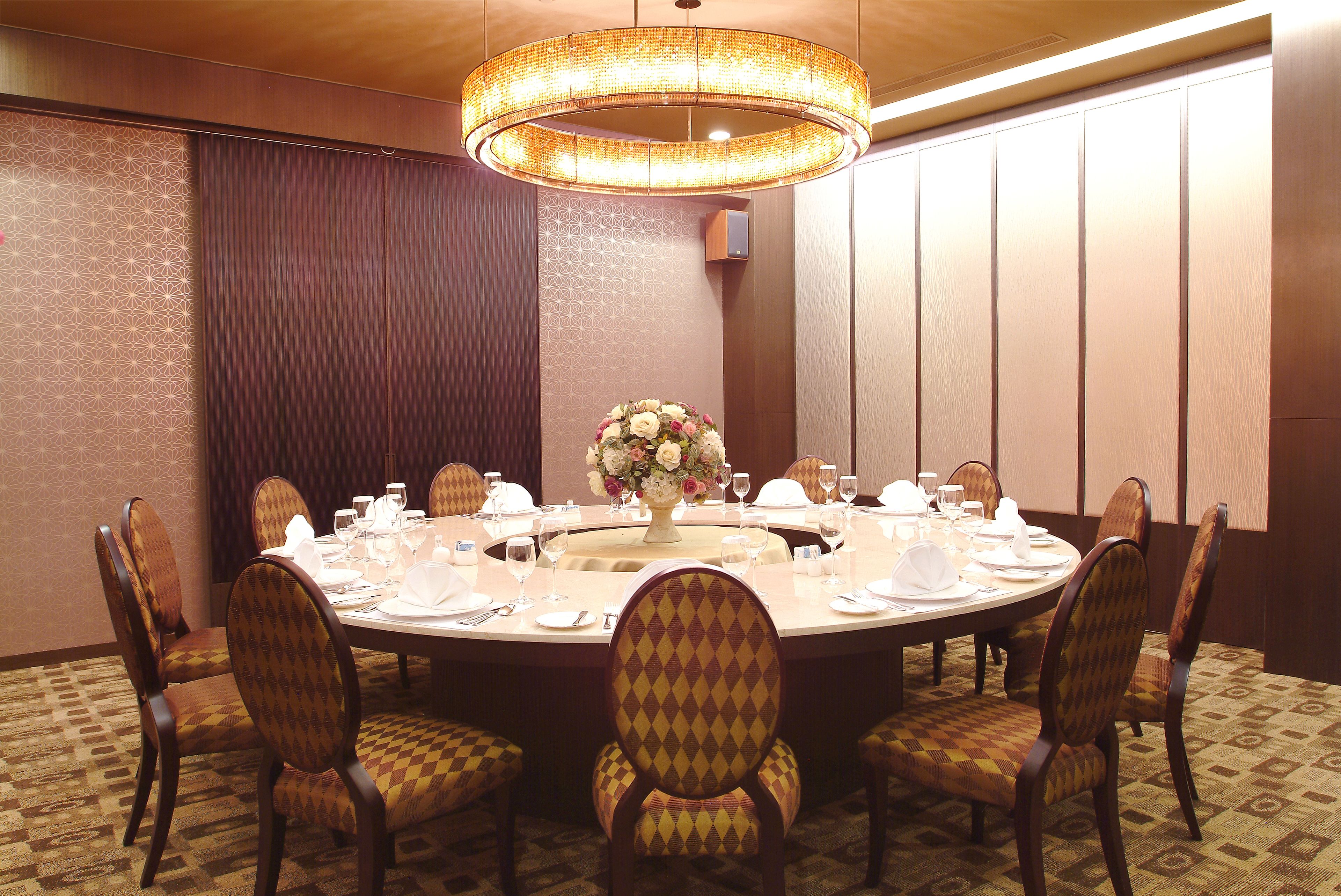 Una mesa redonda de comedor con sillas, un centro de mesa floral y una araña.