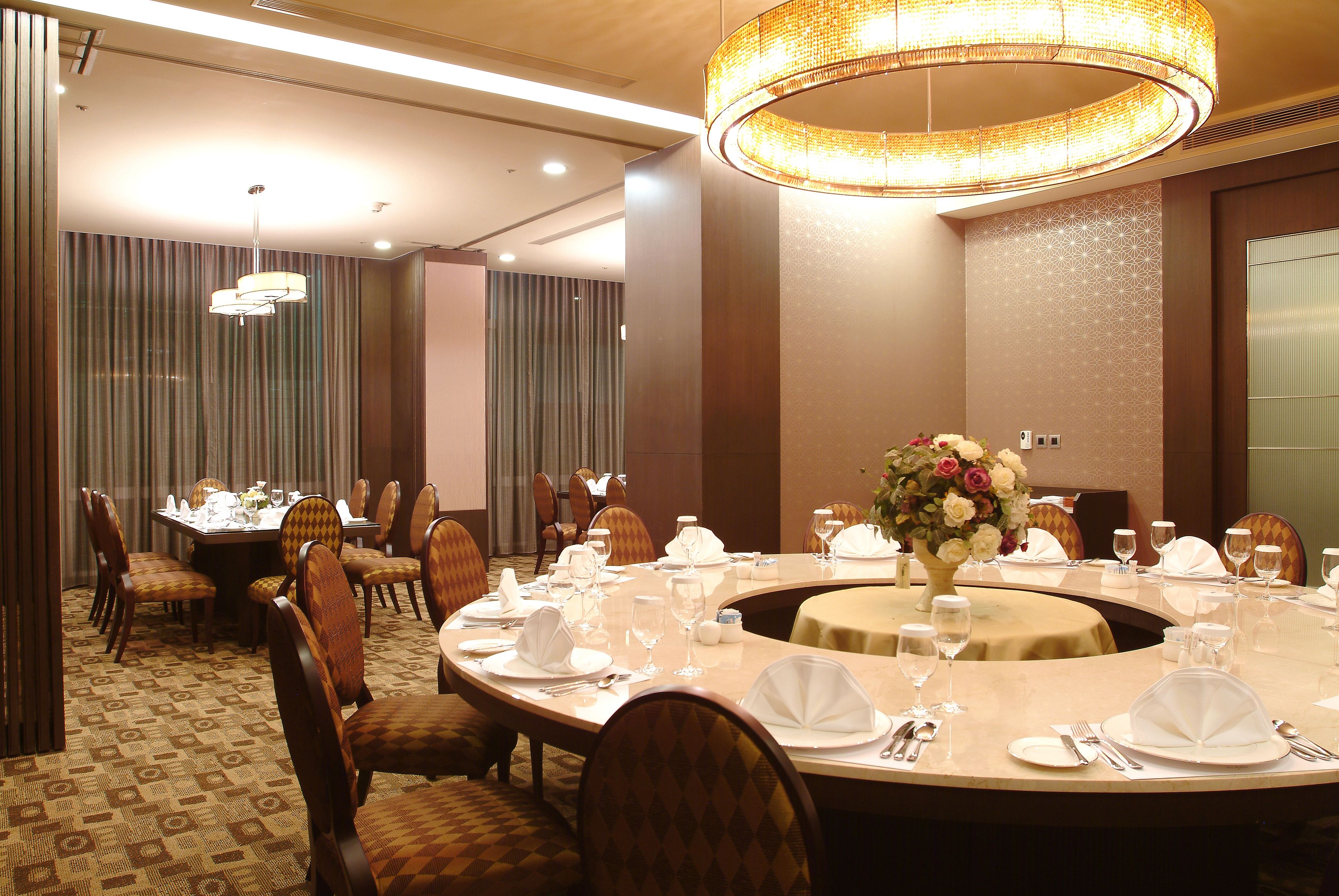 A conference room with round tables, chairs, and a large chandelier.