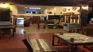A cozy restaurant with wooden furniture, a counter, and a ceiling fan. - Phangan Barsay Hostel (Ko Pha-ngan)