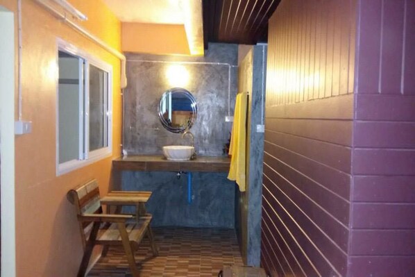 Un baño pequeño con lavamanos, espejo y banco.
