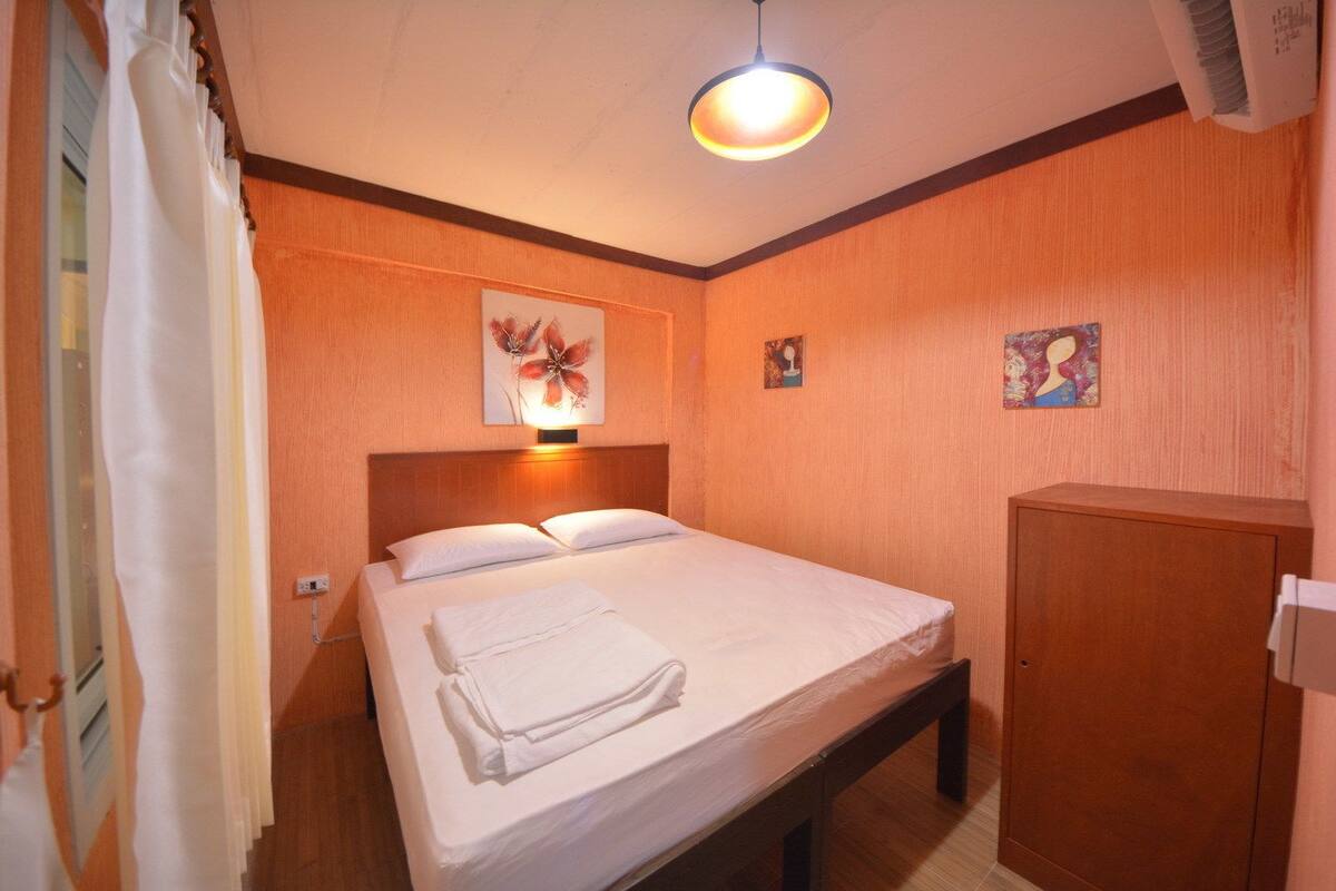 Een hotelkamer met een bed, nachtkastje, kast en een plafondlamp.