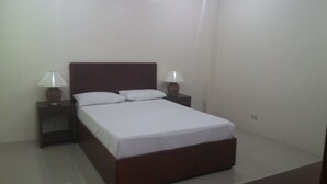 A single bed with a wooden headboard, two bedside tables with lamps, and white bedding.