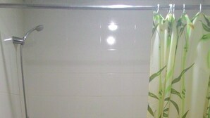 A bathroom with a toilet, a shower, and a sink.