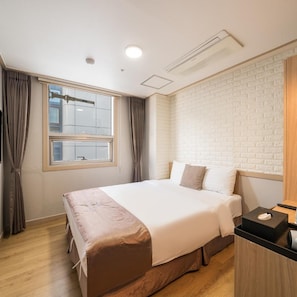 A hotel room with a bed, curtains, a window, a brick wall, and a wooden floor. - The Stay Hotel (Seoul)