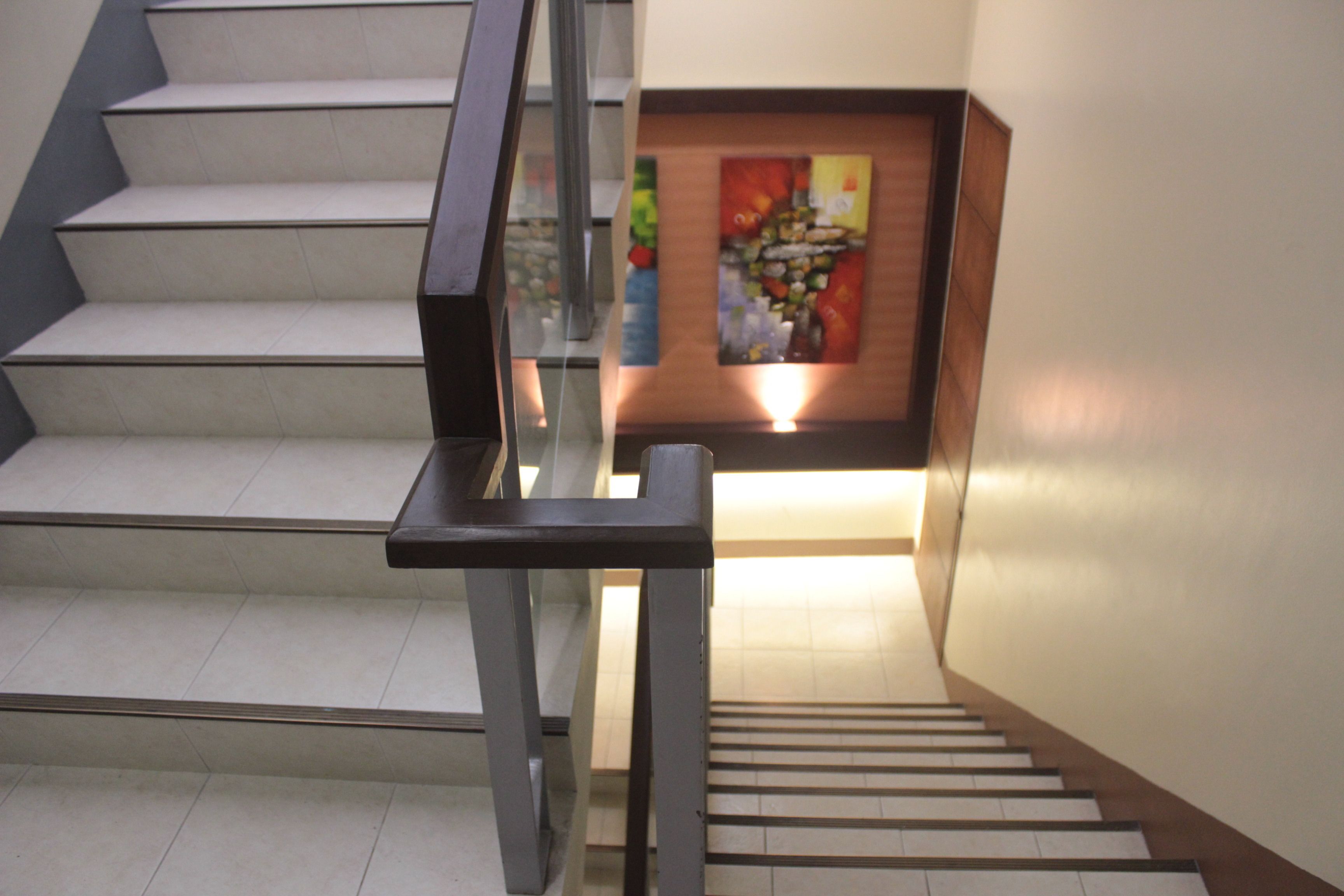 Una escalera con barandilla de cristal y un cuadro en la pared.