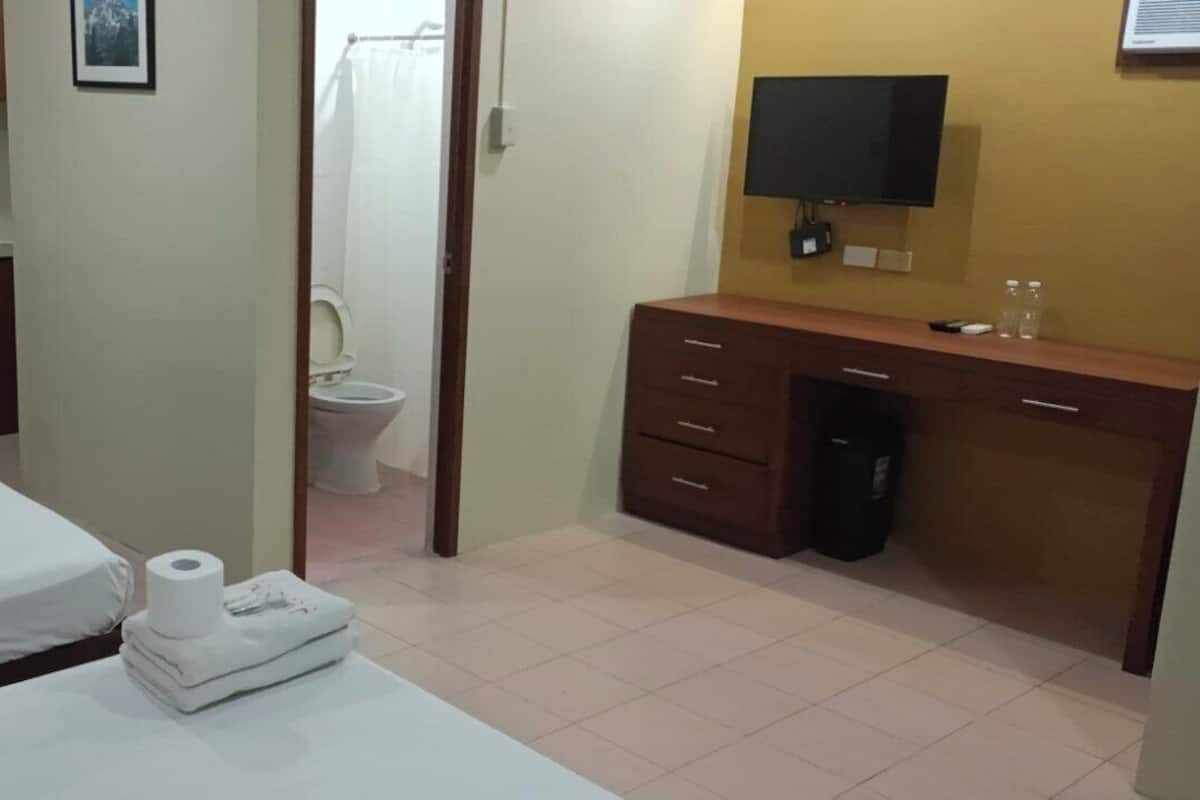 A hotel room with a bed, a small kitchenette, a bathroom, and a TV.