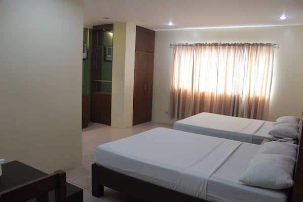 A hotel room with two single beds, a small table, and a wardrobe.