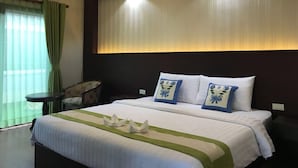 A hotel room with a large bed, a small table, a chair, and a window with curtains. - Saysamphanh Hotel (Luang Prabang)