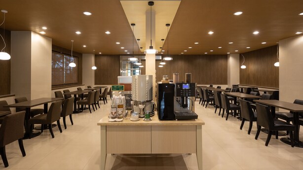A spacious cafe with multiple tables and chairs, a coffee machine, and a water dispenser. - Kindness Hotel Min Sheng (Tainan)