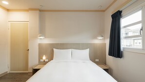 A neatly arranged hotel room with a large bed, bedside tables, and a window with curtains. - Kindness Hotel Min Sheng (Tainan)