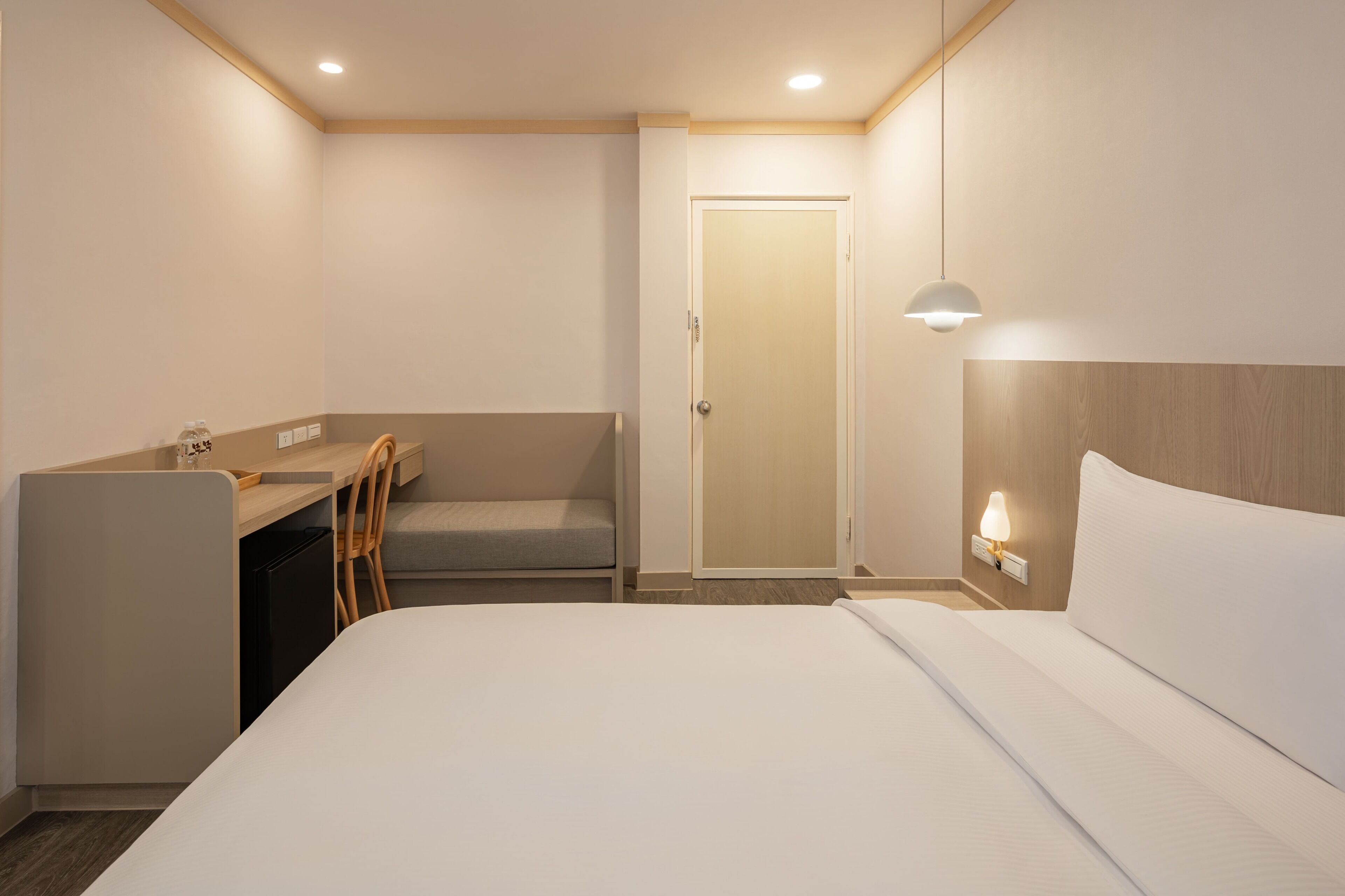 Una habitación de hotel con una cama, un escritorio, una silla, un armario y una puerta.