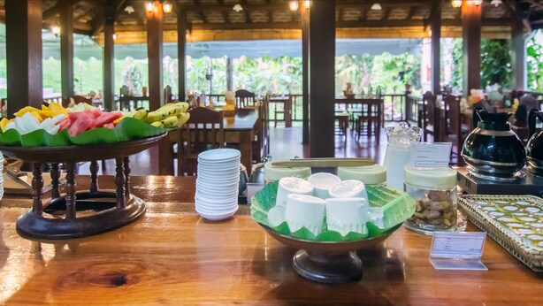 Una mesa de buffet con diferentes alimentos y vistas a un espacio exterior con mesas y sillas.