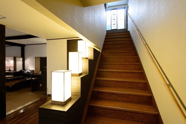 A staircase with wooden steps and a handrail, leading to a landing with a window. - Yubatake Souan (Kusatsu)