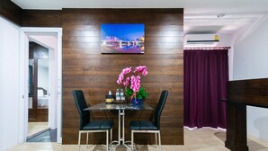 A dining area with a wooden wall, a table with chairs, a vase of flowers, and a painting above the table.