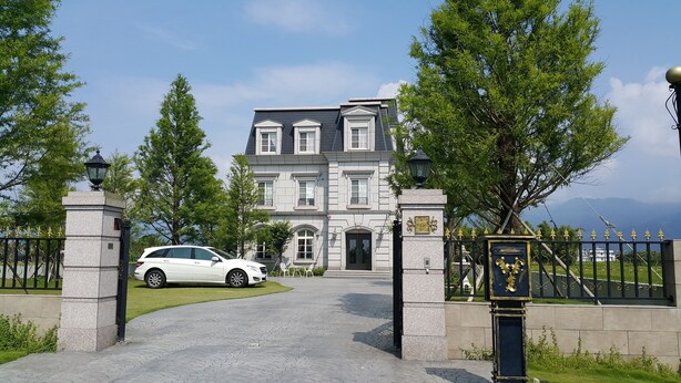 A large, stately building with a grand entrance, a driveway, and a gated area with a car parked in front. - Haut-Rhin Villa (Zhuangwei)
