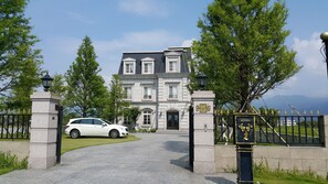 A large, stately building with a grand entrance, a driveway, and a gated area with a car parked in front. - Haut-Rhin Villa (Zhuangwei)