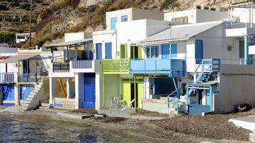 A coastal building with multiple balconies, a staircase, and a chair on the ground floor.