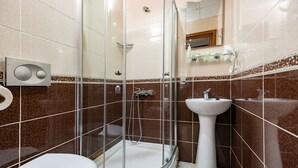 Un baño con ducha de vidrio, lavamanos blanco y un inodoro.
