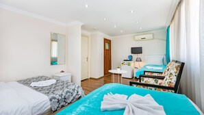 Habitación de hotel con dos camas, una kitchenette pequeña, un televisor y un baño.