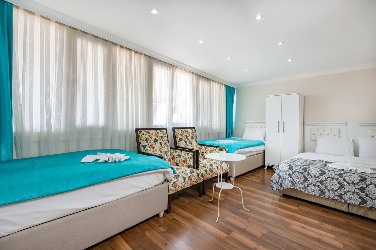 A hotel room with two beds, a small table, and a wardrobe.