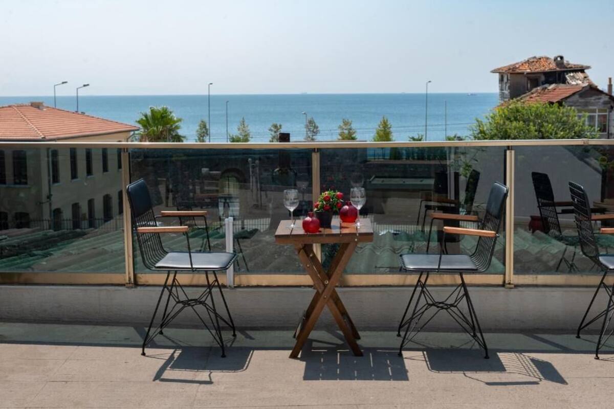 A balcony with a table and chairs, overlooking a coastal view.