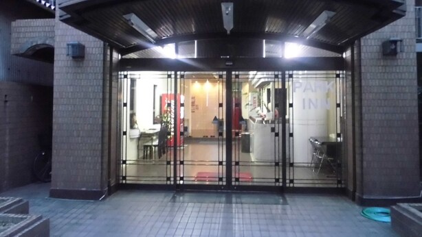 Entrada de hotel con puerta de cristal, zona de acceso cubierta y un cartel que dice 'PARK INN'.