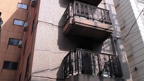 Un edificio de varios pisos con fachada de ladrillo y múltiples balcones con barandillas de metal decorativas.