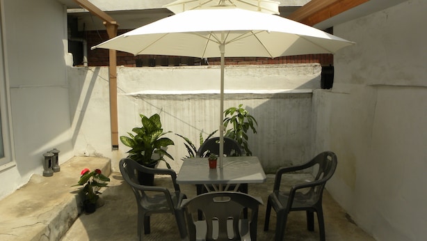 A patio with a table and chairs, an umbrella, and potted plants. - Kame House - Hostel (Seoul)