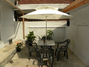 Une terrasse avec une table et des chaises, un parasol et des plantes en pot.