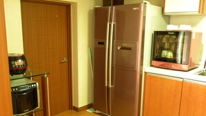 A compact kitchen with a refrigerator, microwave, and oven. - Kame House - Hostel (Seoul)