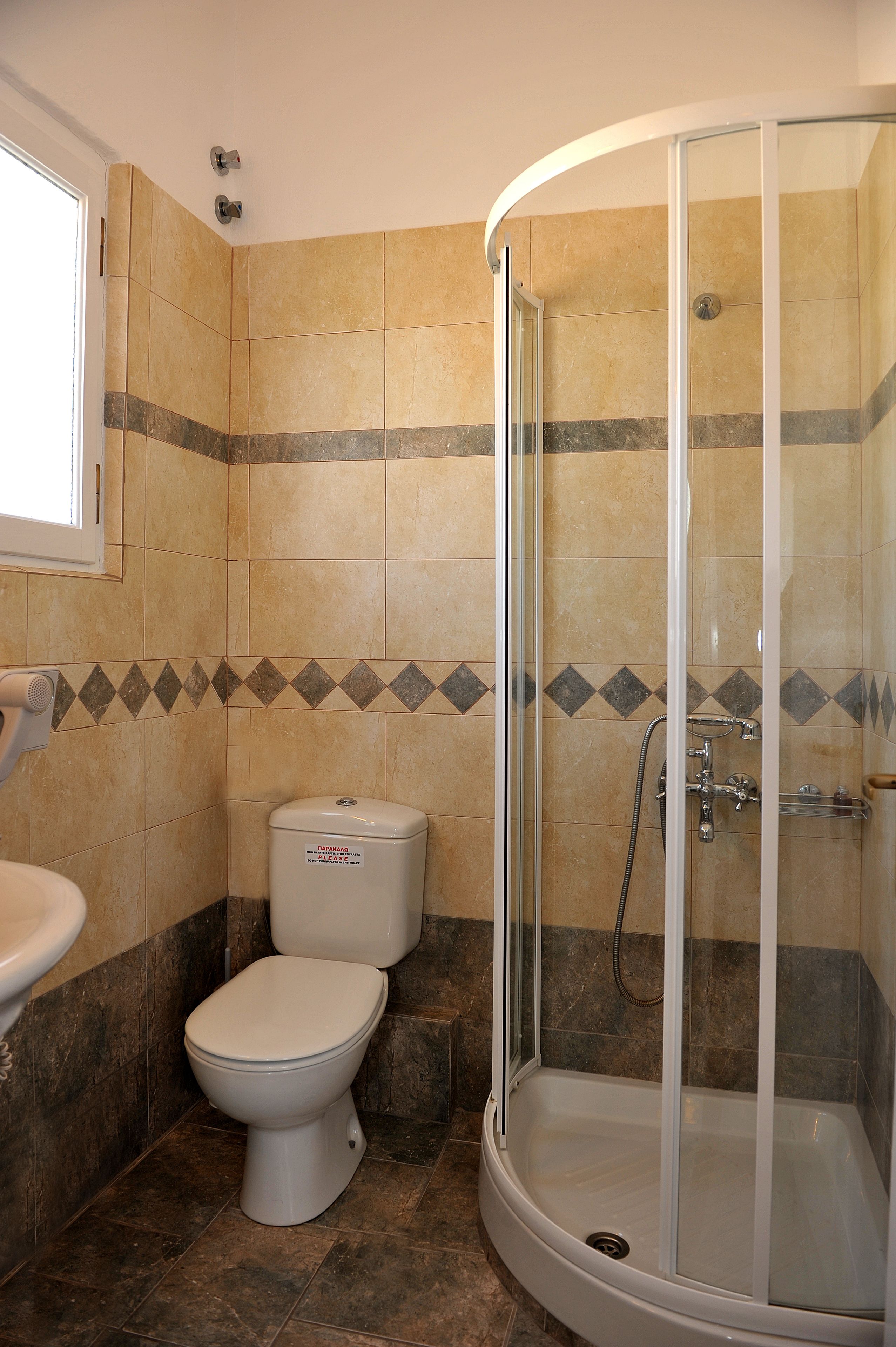 Een badkamer met toilet, wastafel en een douchecabine met glazen wanden.