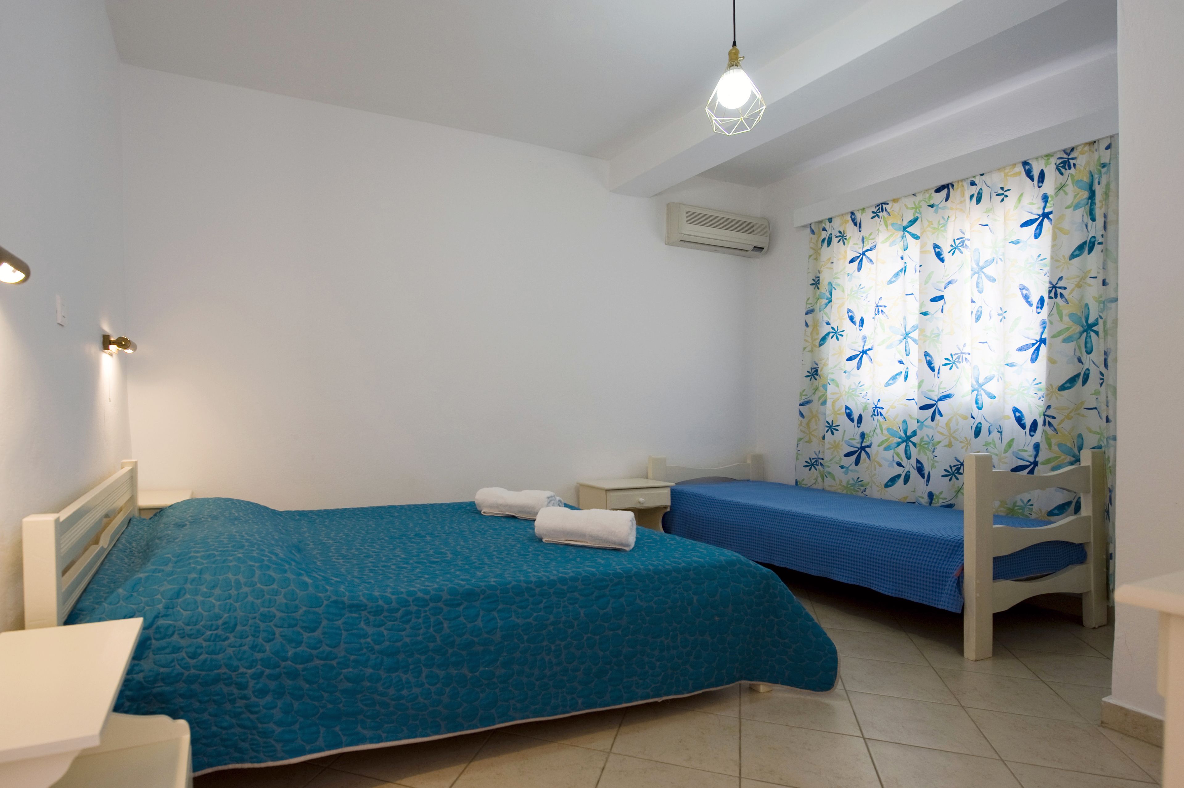 A bedroom with two beds, a desk, a chair, and a ceiling light.