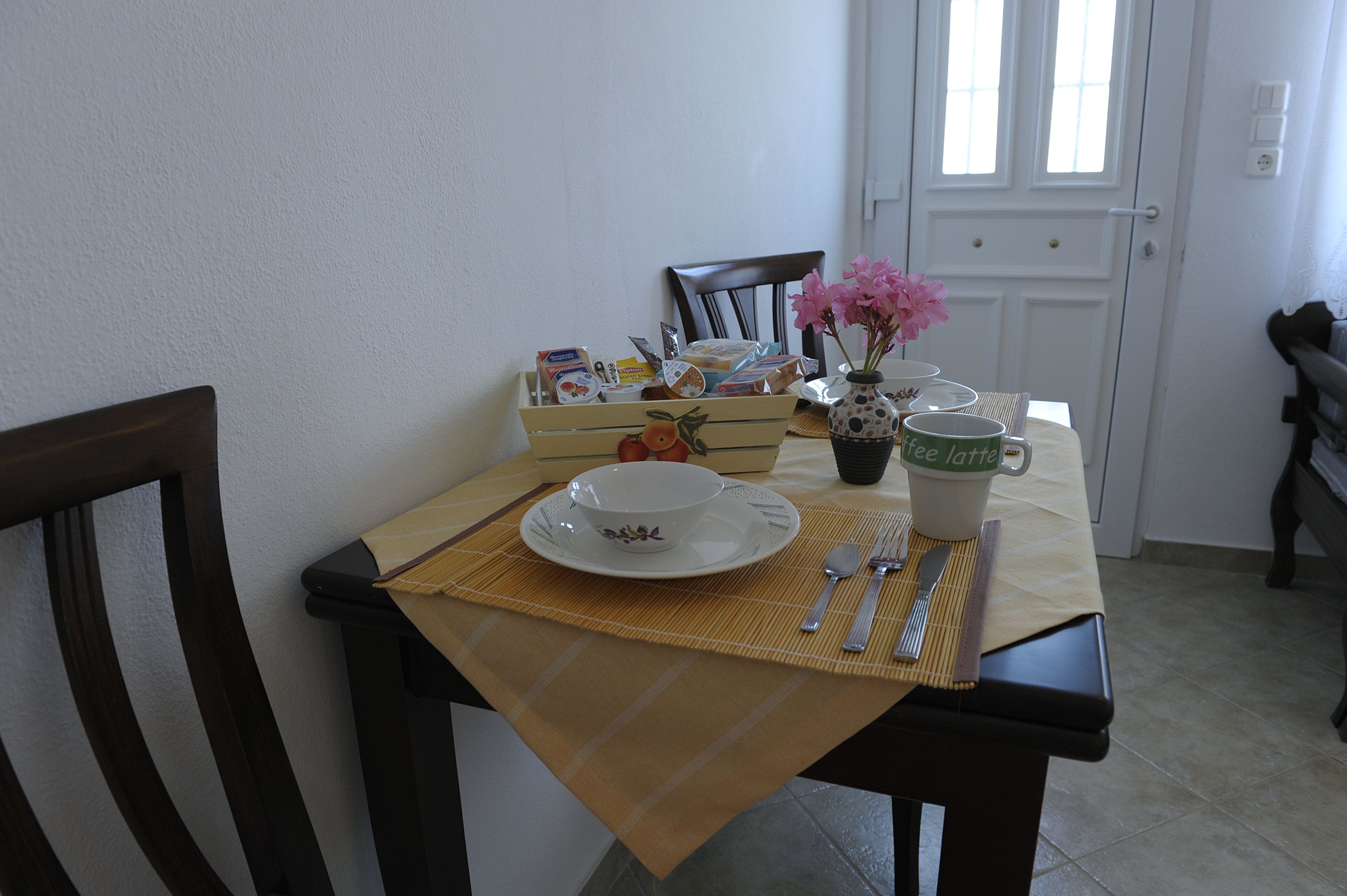 Una mesa de comedor con un mantel individual, un tazón, una taza y un florero con flores.