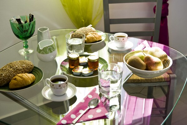 Een glazen tafel met diverse etenswaren, bekers en een glas water.