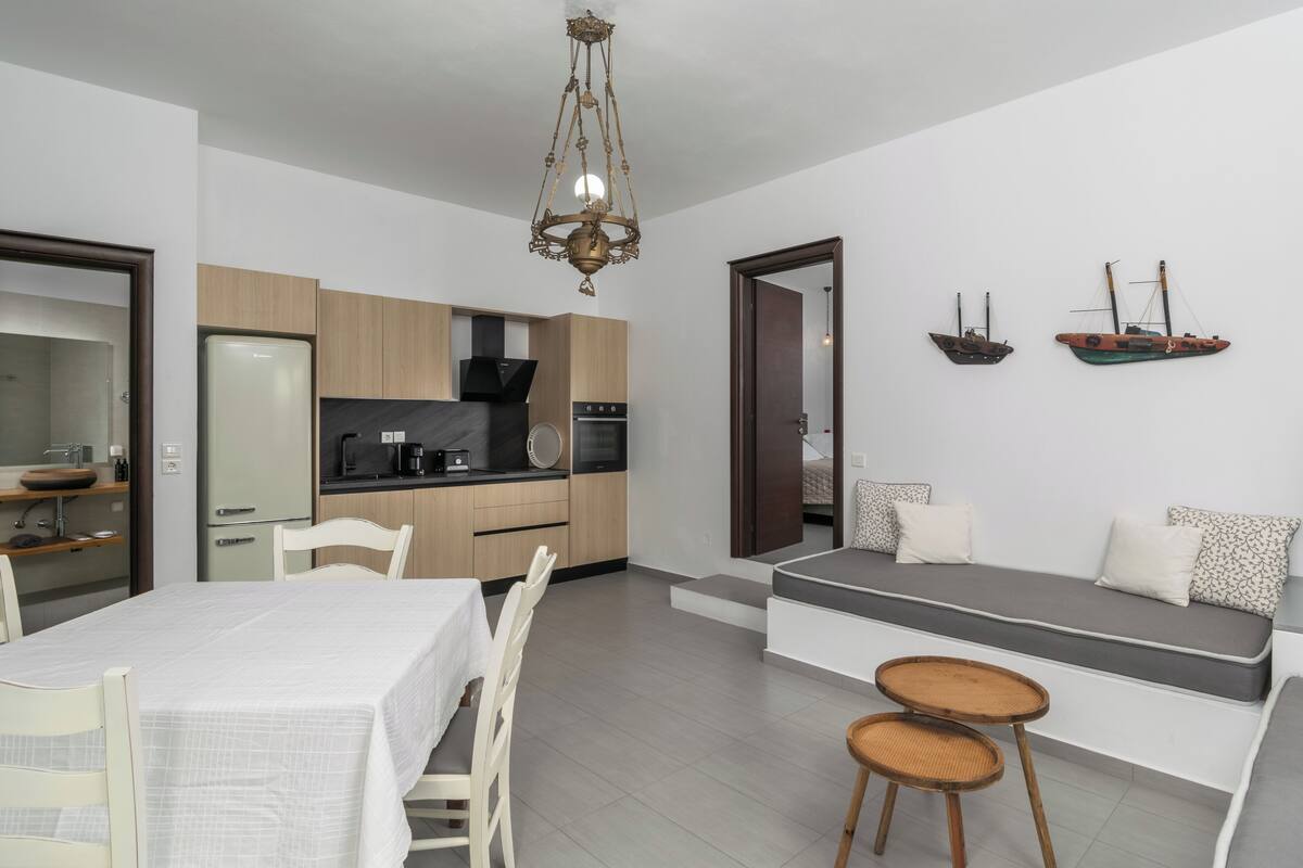 A modern kitchen with wooden cabinets, a dining table, and a built-in bench with cushions.