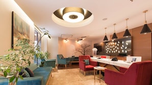 Un salon moderne comprenant un canapé, des fauteuils, une table à manger et un coin cuisine avec des luminaires suspendus.