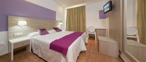 A hotel room with a bed, nightstands, a desk, a chair, a television, and a bathroom with a mirror.